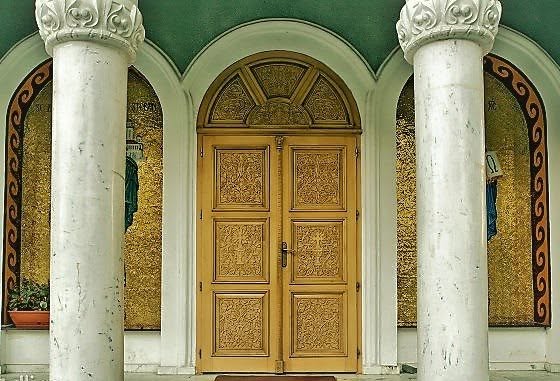 Intrarea Bisericii Sfântul Ștefan din Zalău cu coloane din piatră naturală și ușă decorativă