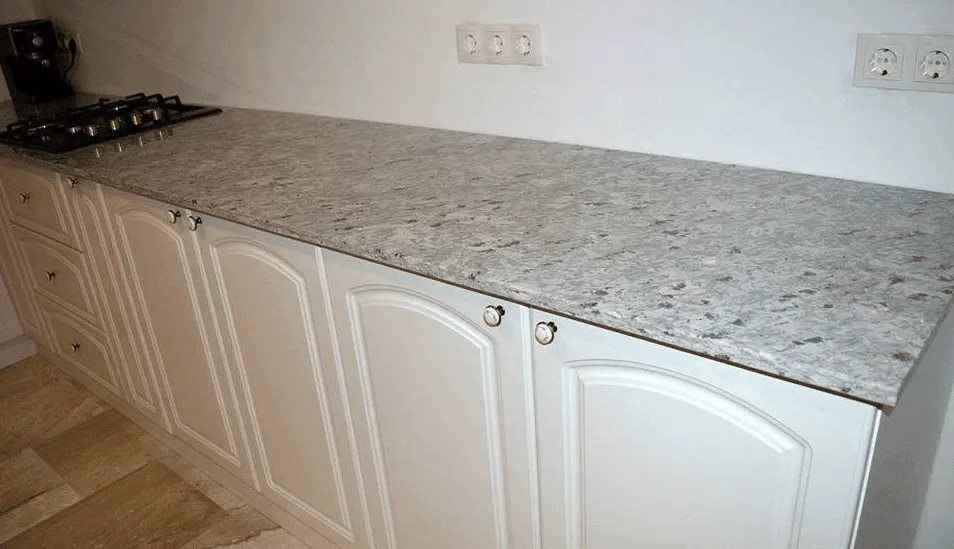 Blat de bucătărie din granit alb gri montat pe mobilier clasic alb cu fronturi decorative