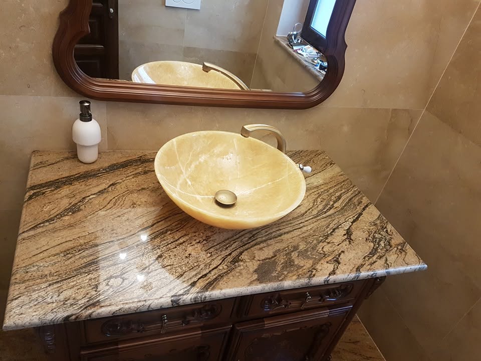 Lavoar din onix crem montat pe blat din granit natural cu modele maro și bej într-o baie elegantă